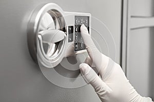 Woman in gloves entering code on keypad of safe, closeup