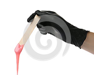 Woman in gloves holding spatula with hot depilatory wax on white background, closeup