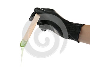 Woman in gloves holding spatula with hot depilatory wax on white background, closeup