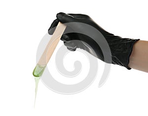Woman in gloves holding spatula with hot depilatory wax on white background, closeup photo
