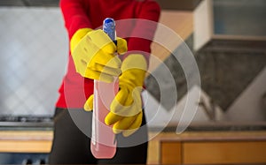 Woman with  gloves holds a disinfectant spray in her hand