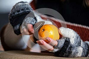 A woman with gloves peels an orange