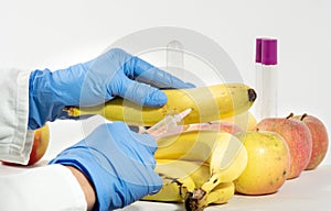 Woman with gloves uses a syringe. Genetic modification of fruits and vegetables