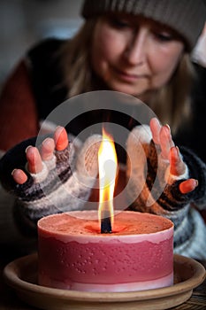 A woman with gloves warms her hands