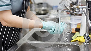 Woman in gloves washing hands in the kitchen, panorama