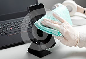 Woman in gloves wipes phomewith wet tissue and disinfectant during covid 19. Protection hygiene prevention from infection, germs,