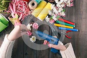 Woman glue handmade flowers with melt gun