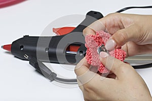 A woman glues a metal hairpin to a knitted brooch in the form of a flower.