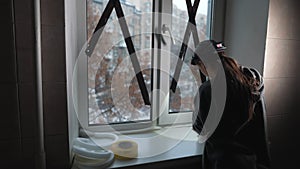 Woman glues a sealing rubber tape on a window