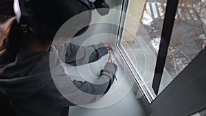 Woman glues a sealing rubber tape on a window