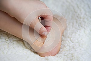 A woman glues a tissue plaster to a corn on her leg