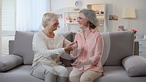 Woman and godmother laughing together holding hands, family communication, fun