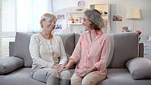 Woman and godmother laughing together, holding hands, family communication, fun