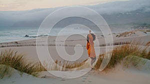 Woman going down hill waving hand summer evening. Girl relaxing on seashore.