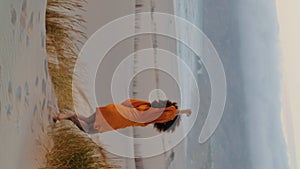 Woman going down hill waving hand summer evening vertical. Girl on seashore.