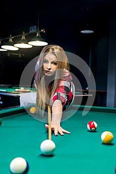 Woman going hit a ball with cue in billiard