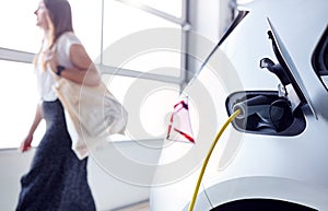 Woman Going Shopping Whilst Leaving Electric Vehicle To Charge In Car Park