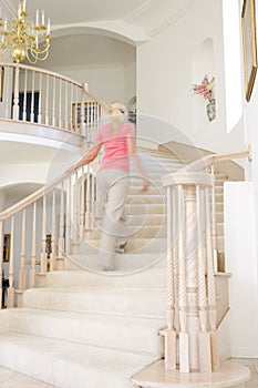 Woman going up staircase in luxurious home