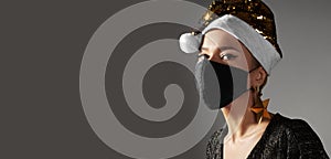 Woman with gold christmas hat, black medical mask. Fashion shiny style for xmas time. Protection from flu on holidays