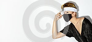 Woman with gold christmas hat, black medical mask. Fashion shiny style for xmas time. Protection from flu on holidays