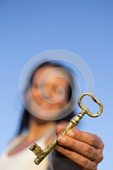 Woman gold key in hand blue sky