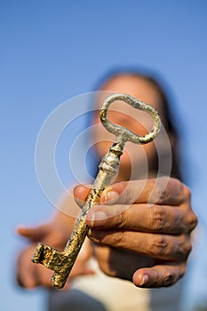 Woman gold key in hand blue sky