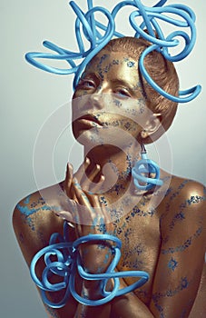 Woman with golden body-art and blue tubes