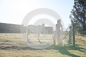 Woman in golden dress next to white horse