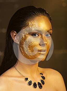 Woman with golden makeup and bodyart