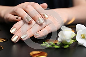 Woman with golden manicure on black table