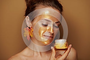 Woman with golden mask enjoying fragrance of cosmetic product