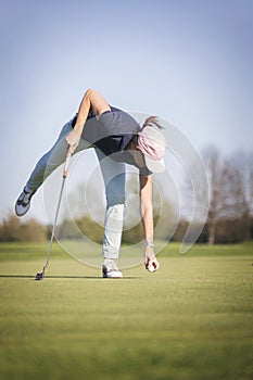 Woman golf player pick up ball.