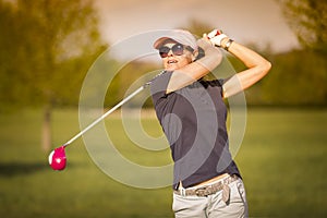 Woman golf player teeing off.