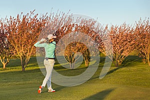 Woman golf player teeing-off.