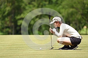 Woman golfer check line for putting golf ball on green grass