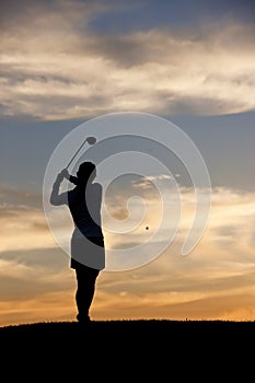 Woman golfer hits ball.