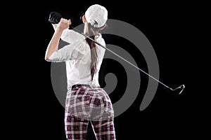 Woman golfer hitting the ball isolated on black background. Copy space. Ad concept.