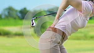 Woman golfer making backswing hitting ball and feeling sharp lower back pain