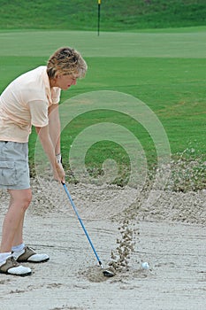 Woman golfer in a sand bunker