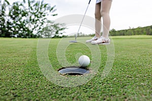 woman golfer teeing golf in golf tournament competition at golf course, selective focus on golf ball