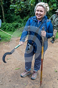 Woman on a gorilla trek in Uganda holds a machete in prepration for her hike to see mountain gorillas