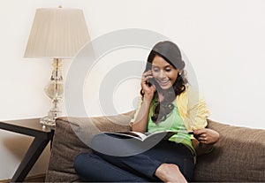 Woman gossiping on mobile phone and reading a magazine