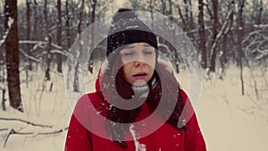 A woman got lost in the forest in winter, she looks around in search of a way. Female in a warm red jacket is scared