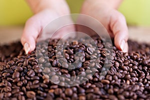 Woman grabbing a handful of roasted coffee beans