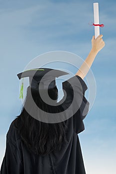 Woman in graduation gown rejoicing success