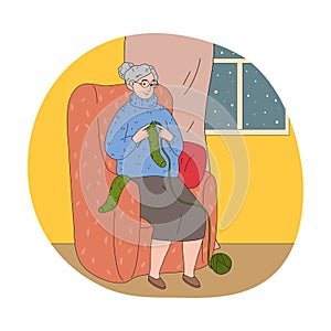 Woman grandmother sitting in armchair and knitting green warm socks