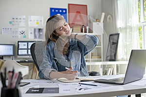 Woman graphic designer businesswoman feeling pain in neck after sitting at the table with laptop.