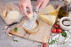 Woman grates Parmesan cheese on a wooden cutting board at domestic kitchen