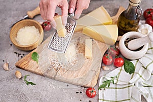 Woman grates Parmesan cheese on a wooden cutting board at domestic kitchen