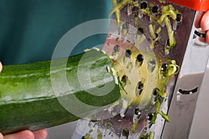 woman grating zucchini with a stainless steel hand grater
